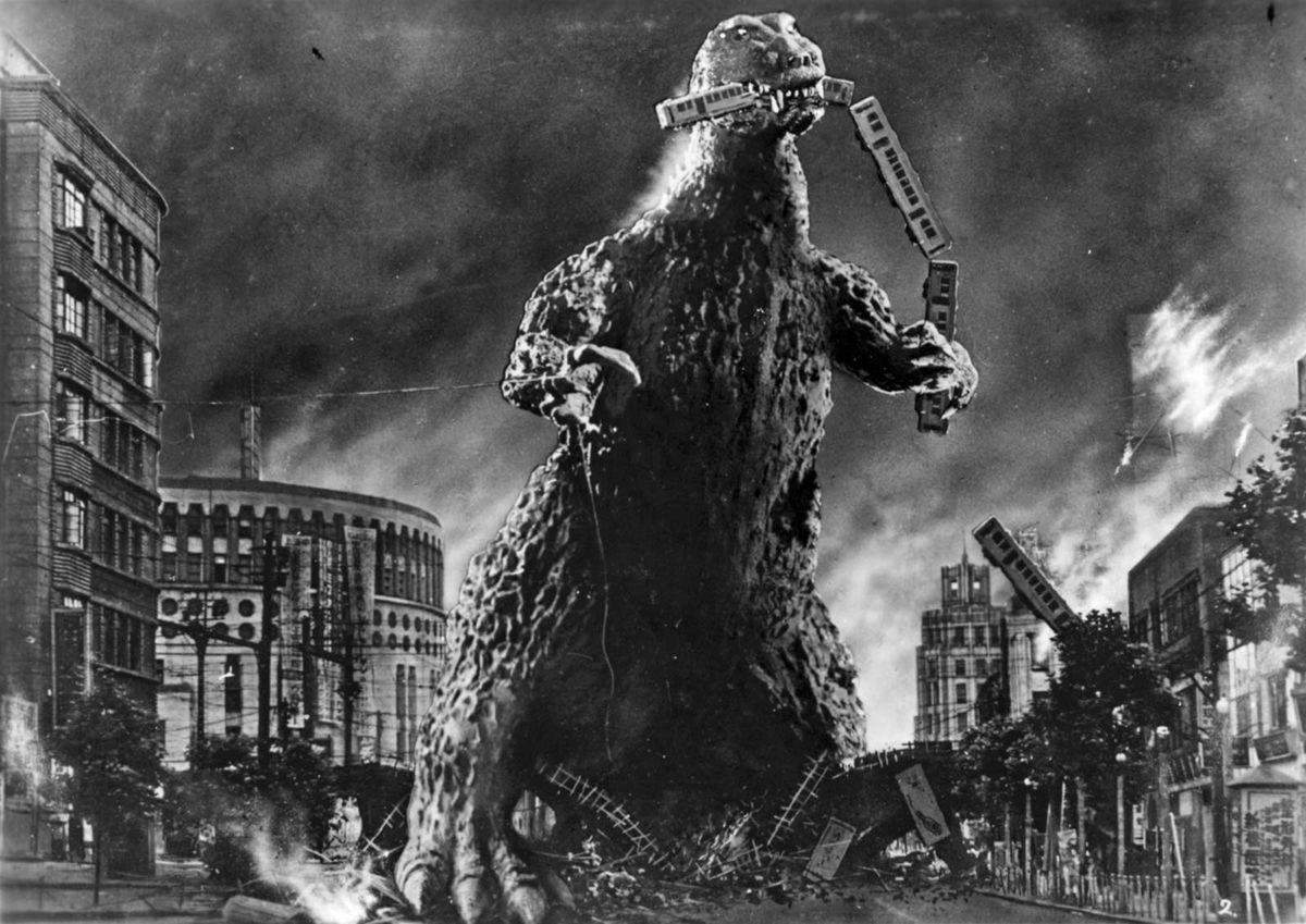 Godzilla tears a line of train cars apart with his teeth