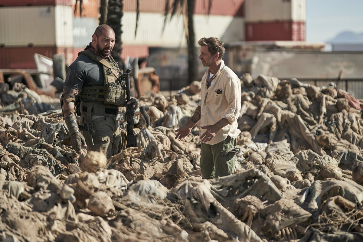 Dave Bautista and Zack Snyder stand in a field of corpses on the Army of the Dead set