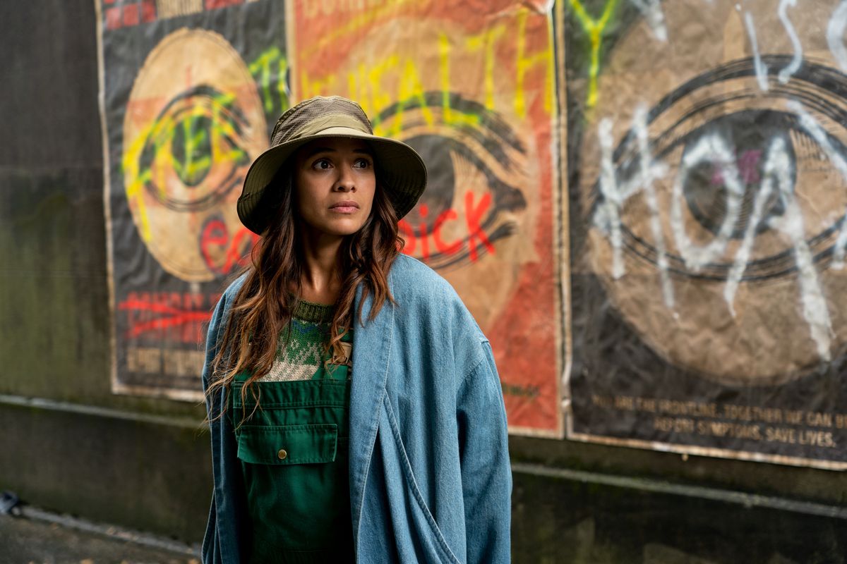 Dania Ramirez stands in front of a wall covered in graffiti proclaiming “free the healthy” and other slogans about a virus called the Sick, as Aimee in episode 104 of Sweet Tooth.