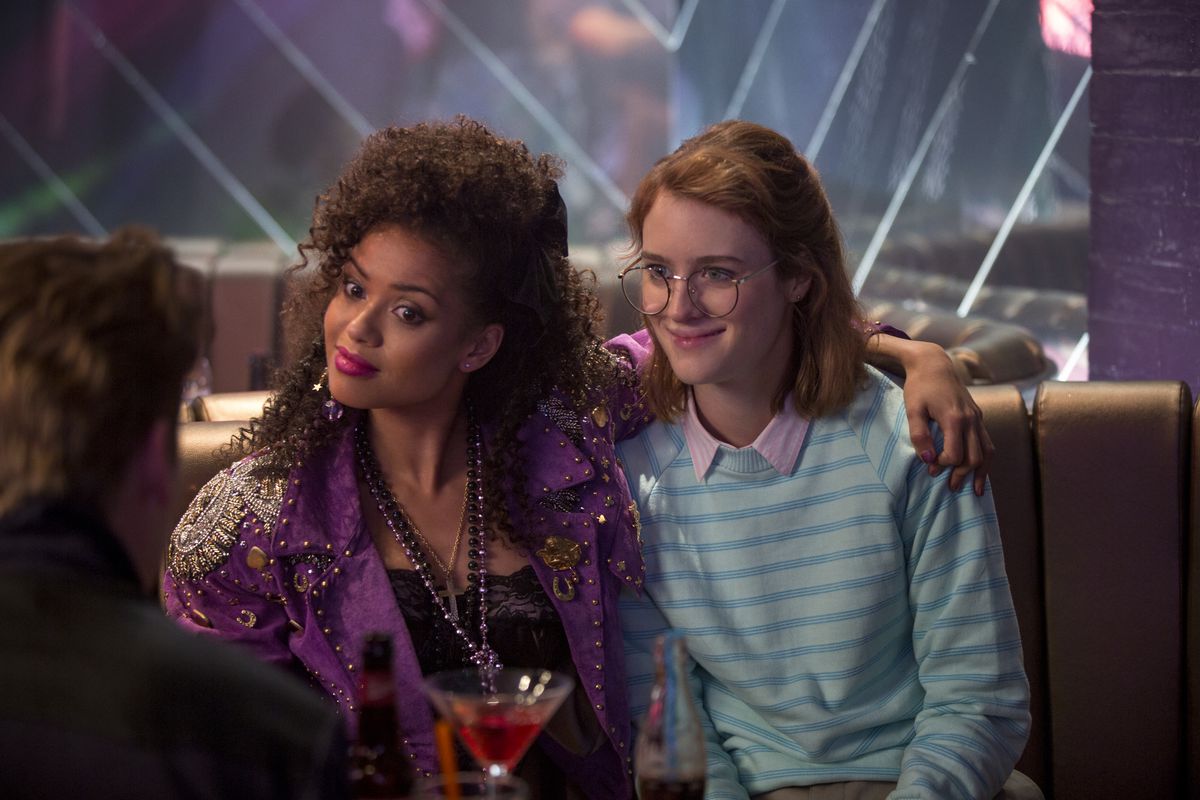 A dark-skinned woman in a heavily decorated purple jacket sits in a bar booth with her arm around a nerdy-looking, nervously smiling pale woman in a striped polo and round glasses.