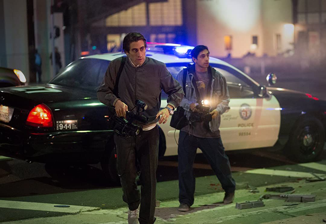 Freelance cameraman Lou Bloom (Jake Gyllenhaal) and his assistant Rick (Riz Ahmed) filming the scene of a car crash in Nightcrawler.