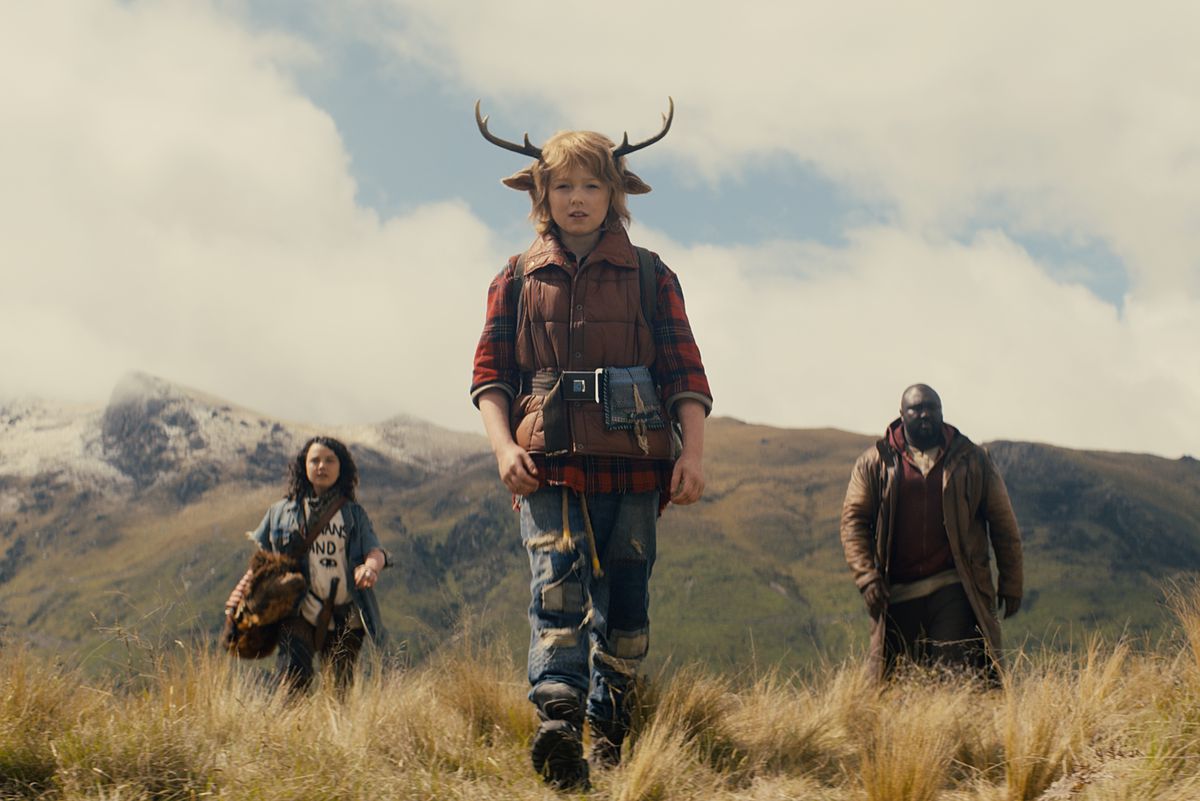 Deer boy Gus (Christian Convery) walks ahead of his adult allies in front of the mountains in season 1 of Netflix’s Sweet Tooth.