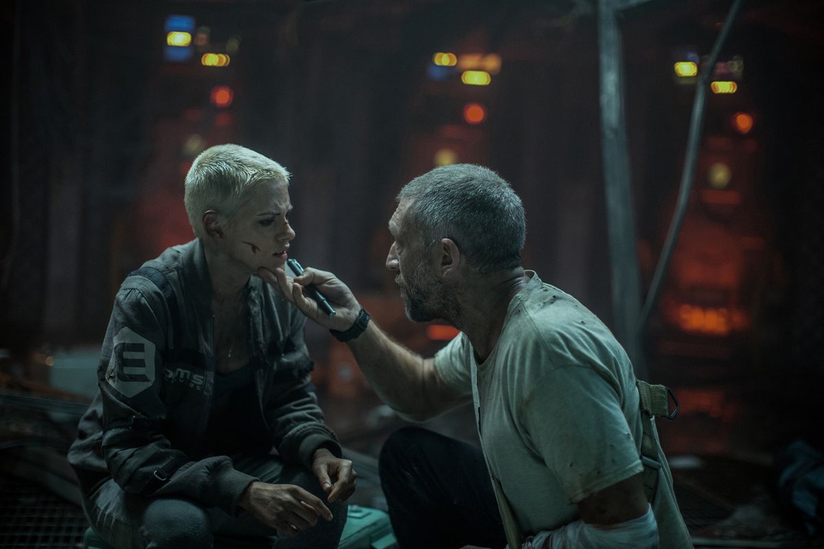 In a control room, the Captain (Cassel) inspects Norah’s (Stewart) facial wounds in Underwater