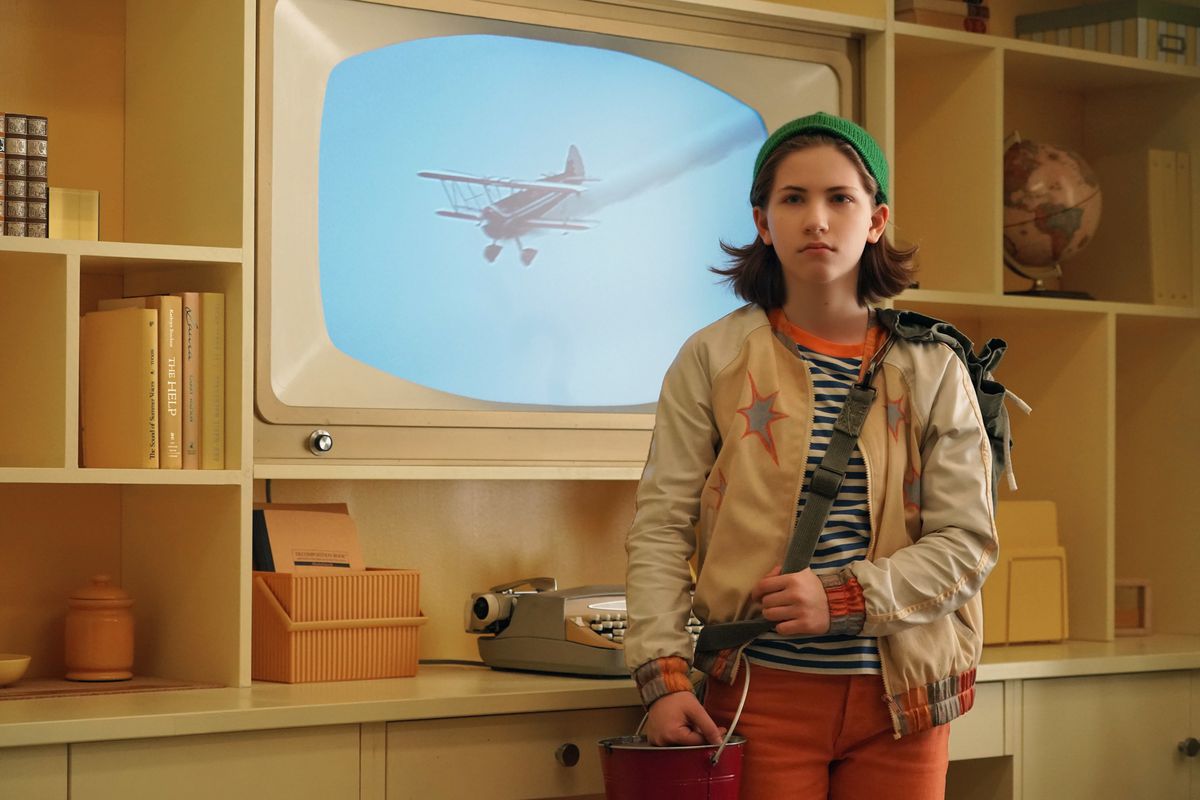 a girl in mismatched clothes standing in front of an old-fashioned tv