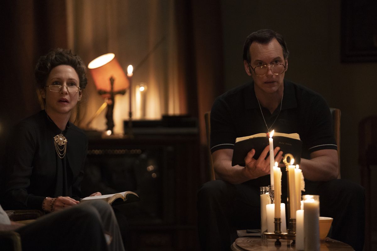 Ed and Lorraine Warren sit with bibles in the candle light in The Conjuring: The Devil Made Me Do It 
