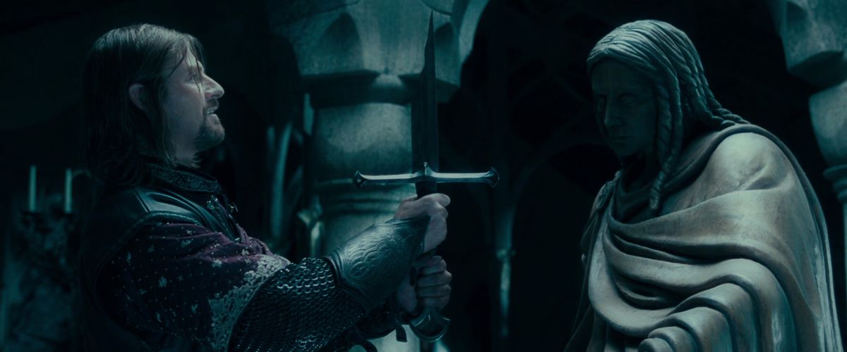 Sean Bean as Boromir lifts the broken sword Narsil with a slight smile in The Fellowship of the Ring