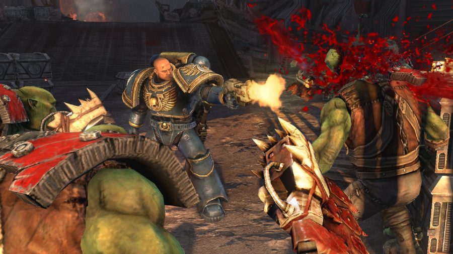 A 40K space marine fires at a couple of orks charging him