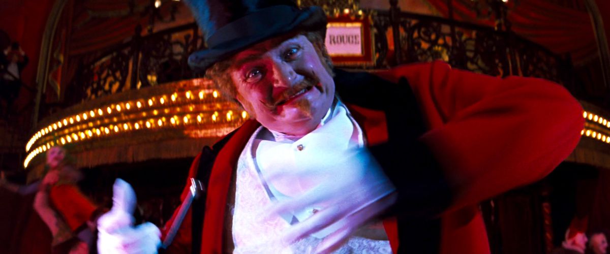 Jim Broadbent, dressed as a ringmaster, lunges at the screen in Moulin Rouge