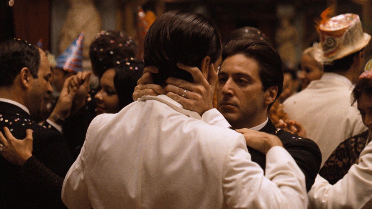 Michael Corleone embraces another man in a threatening manner at a New Years party in The Godfather Part II. 
