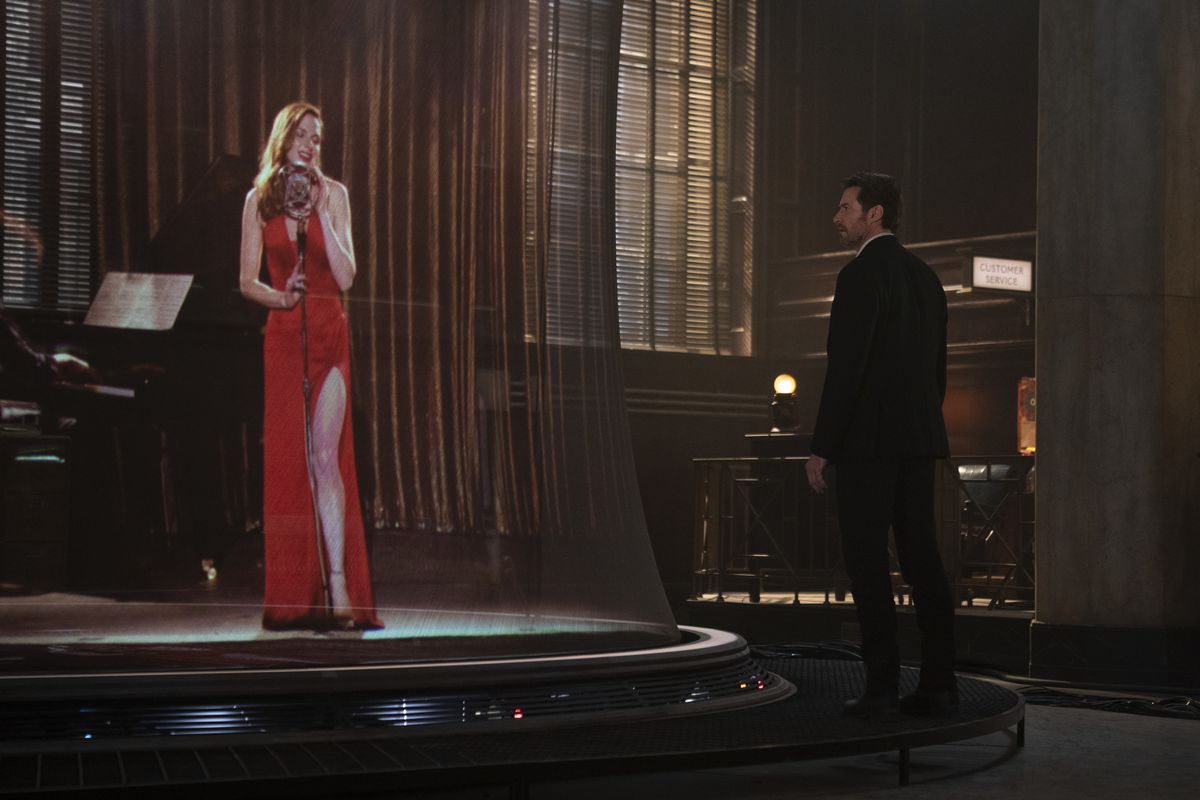 Hugh Jackman stars at a 3D re-creation of Rebecca Ferguson in a slinky red dress, singing in a nightclub, in Reminiscence