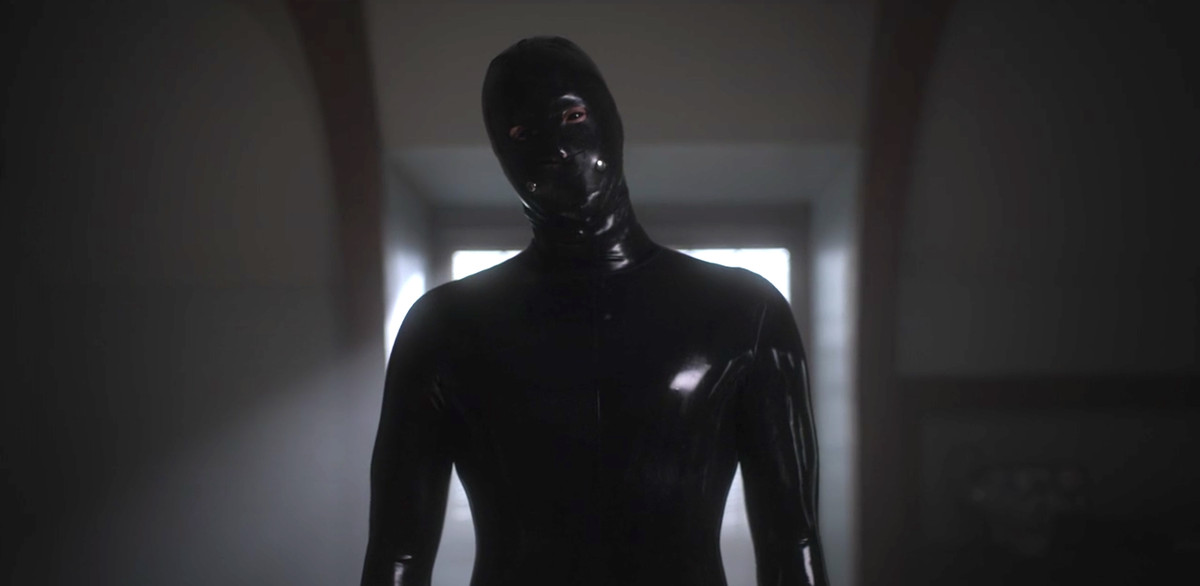 a figure in a black rubber suit