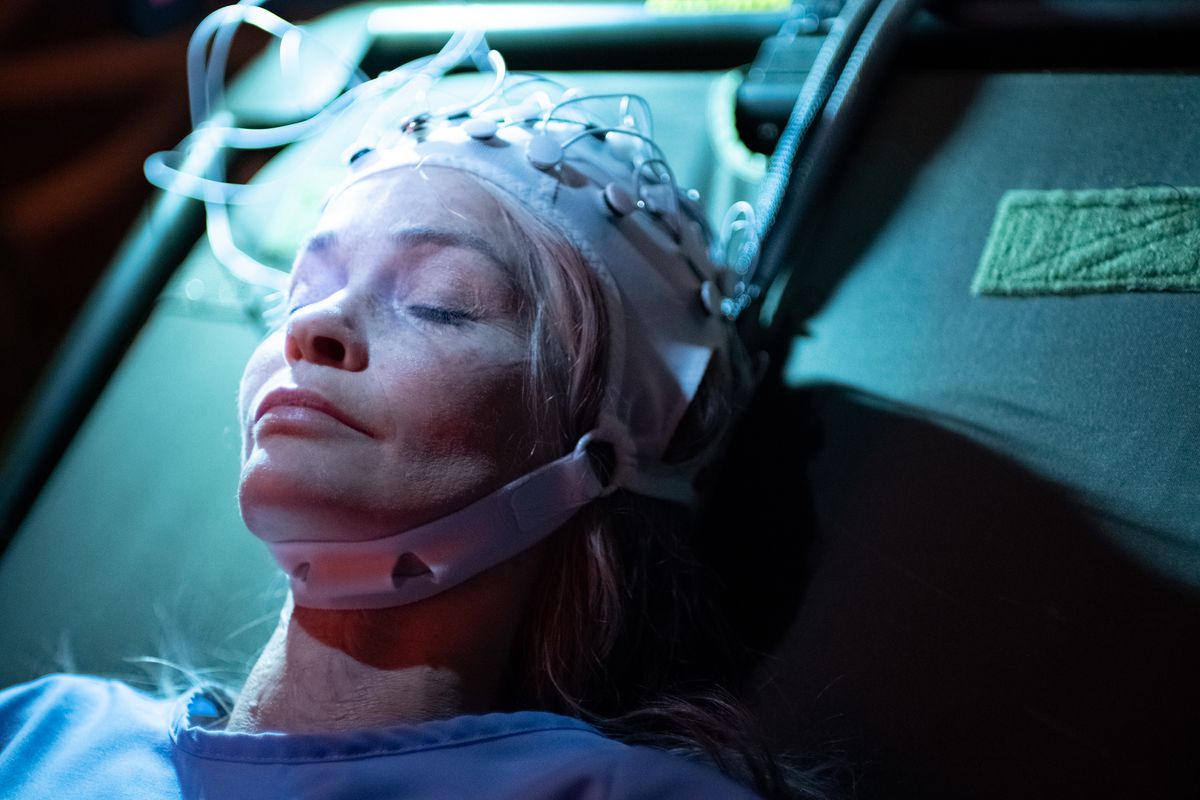 Nathalie Boltt laying on a table with a virtual reality helmet on in Demonic