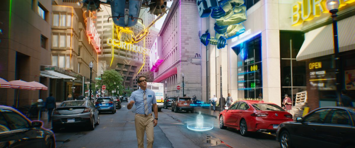 Ryan Reynolds as Guy walking down a street amazed by neon holographic displays in Free Guy.