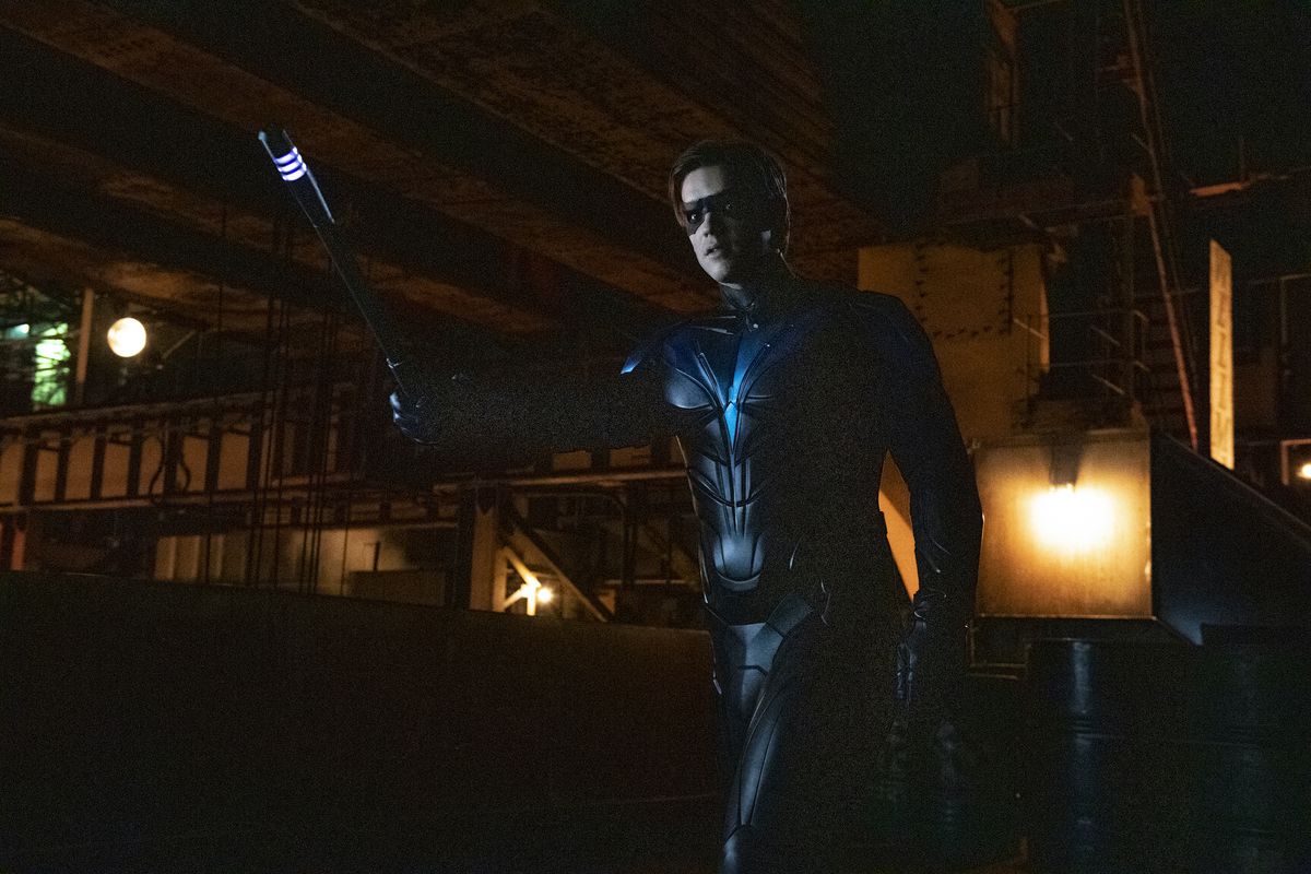 Brenton Thwaites as Robin in Titans season 3, holding up a glowing baton in a warning gesture