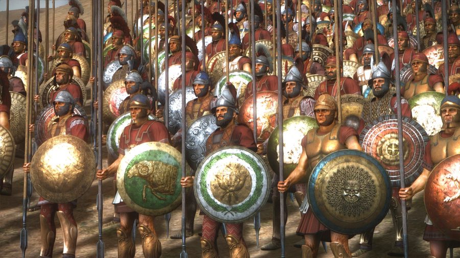 row upon row of greek warriors stand at attention, holding large round shields with spears pointing upwards