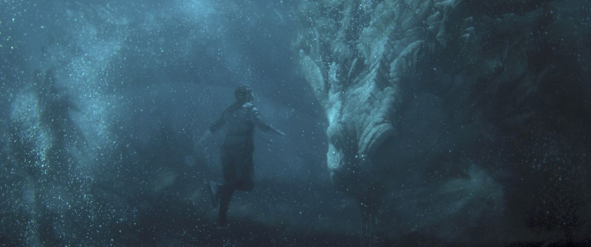 Shang-Chi (Simu Liu) floats underwater in front of a huge Chinese dragon, the Great Protector in Shang-Chi and the Legend of the Ten Rings. 