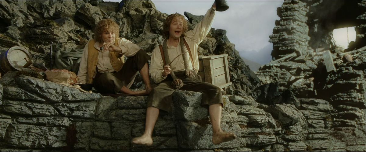 Merry and Pippin greet others excitedly in the wreckage of Isengard in The Return of the King. 